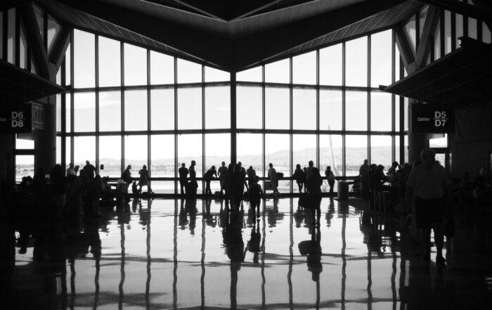 A group of people silhouetted against the window of an airline terminal.