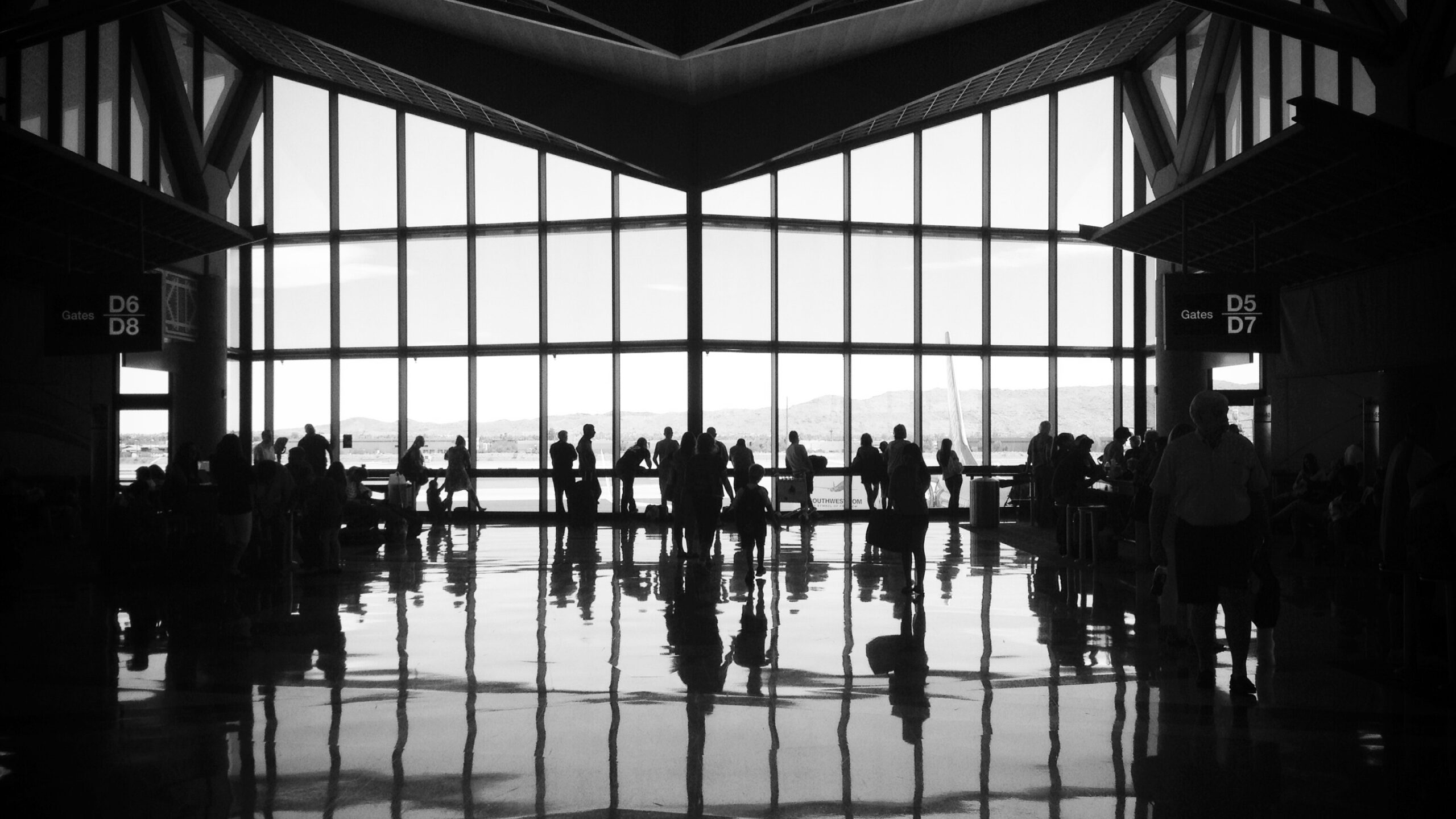 A group of people silhouetted against the window of an airline terminal.